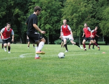 The men's soccer team practicing in red jerseys.